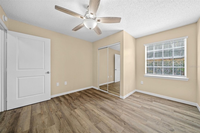 unfurnished bedroom featuring light hardwood / wood-style flooring, a closet, ceiling fan, and a textured ceiling