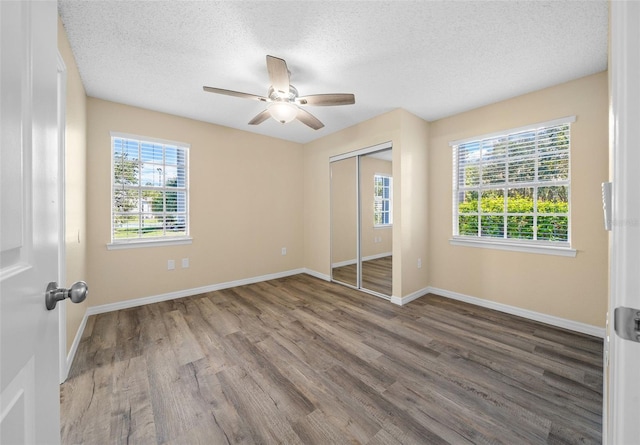 unfurnished bedroom with ceiling fan, hardwood / wood-style flooring, a closet, and a textured ceiling