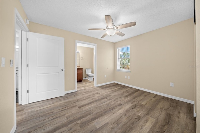 unfurnished bedroom featuring ceiling fan, a textured ceiling, light wood-type flooring, and ensuite bath