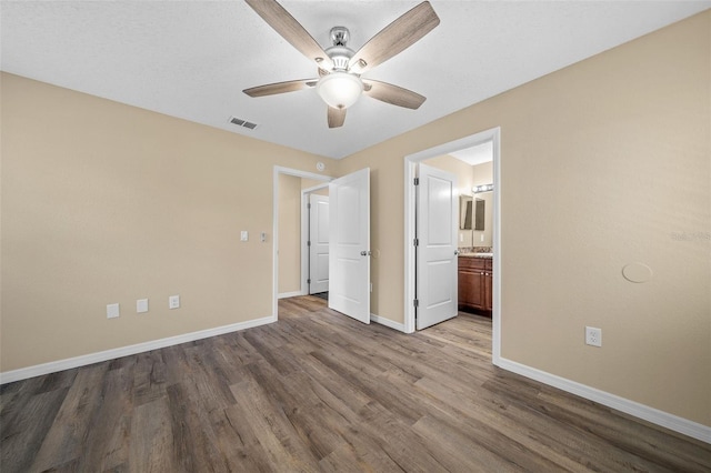 unfurnished bedroom featuring ensuite bath, ceiling fan, and hardwood / wood-style flooring