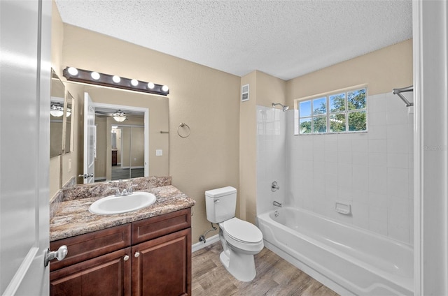 full bathroom with hardwood / wood-style flooring, vanity, ceiling fan, tiled shower / bath, and toilet