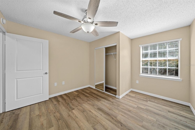 unfurnished bedroom with a textured ceiling, ceiling fan, light hardwood / wood-style flooring, and a closet