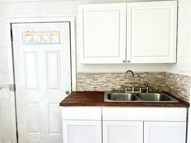 interior space with decorative backsplash, white cabinetry, and sink