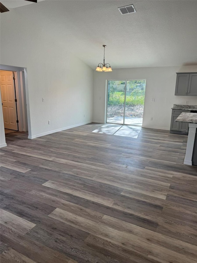 unfurnished living room featuring dark wood-type flooring, a chandelier, high vaulted ceiling, and a textured ceiling