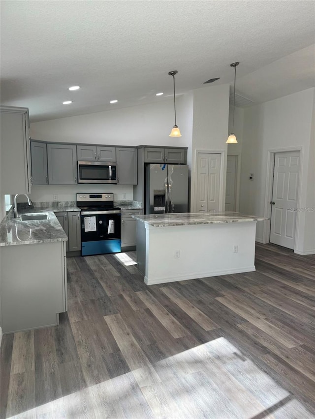 kitchen with sink, decorative light fixtures, appliances with stainless steel finishes, gray cabinets, and a kitchen island