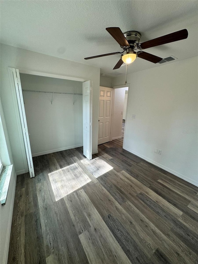 unfurnished bedroom featuring ceiling fan, dark hardwood / wood-style floors, a textured ceiling, and a closet