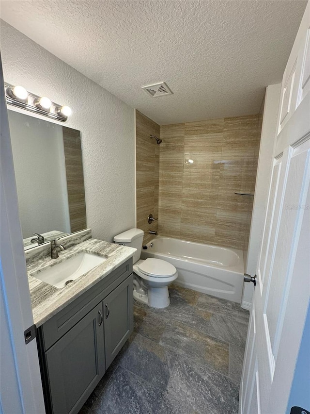 full bathroom featuring tiled shower / bath combo, vanity, a textured ceiling, and toilet