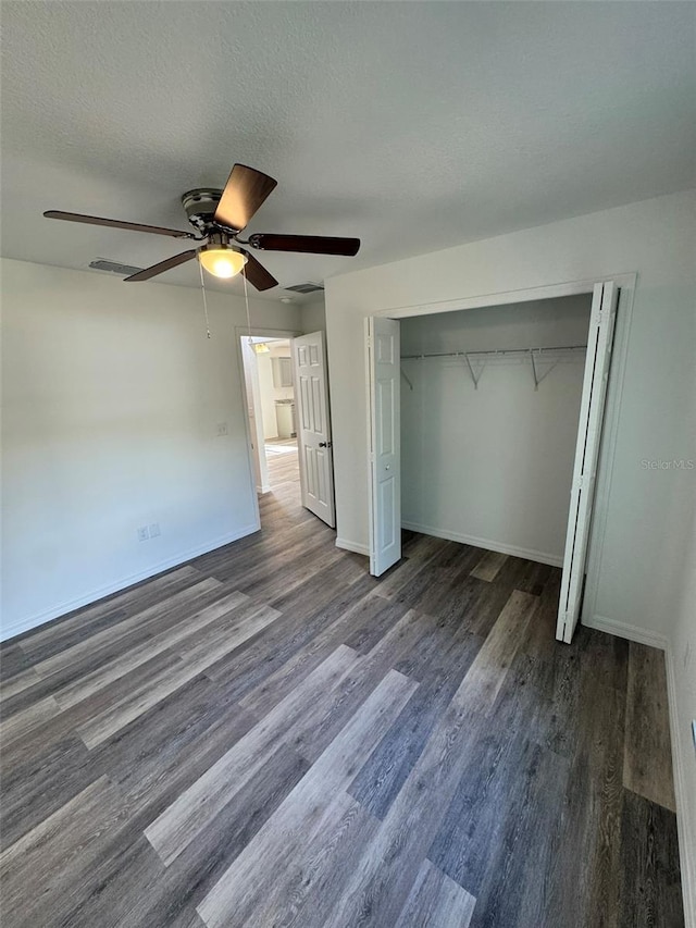 unfurnished bedroom with a closet, dark hardwood / wood-style floors, a textured ceiling, and ceiling fan