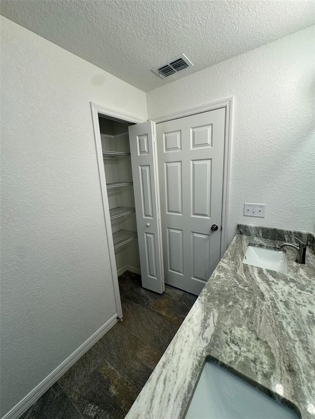 bedroom with a closet, sink, and a textured ceiling