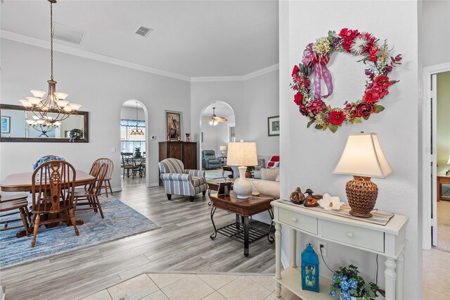 living room featuring ceiling fan with notable chandelier, light hardwood / wood-style flooring, and crown molding