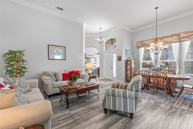 living room with ornamental molding, a notable chandelier, and wood-type flooring