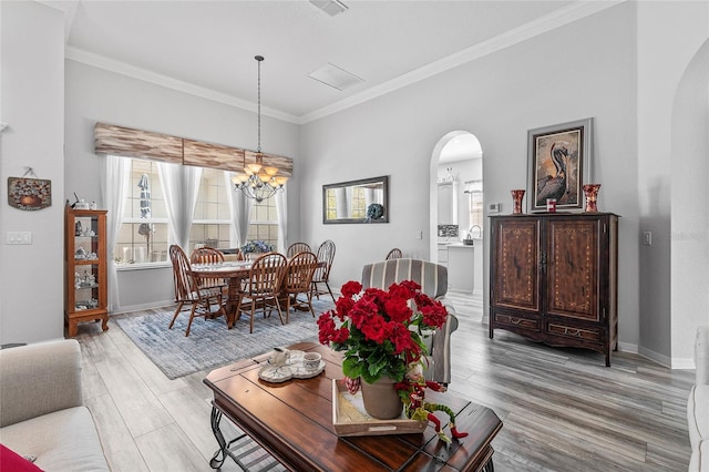 living room with a notable chandelier, crown molding, and light hardwood / wood-style flooring