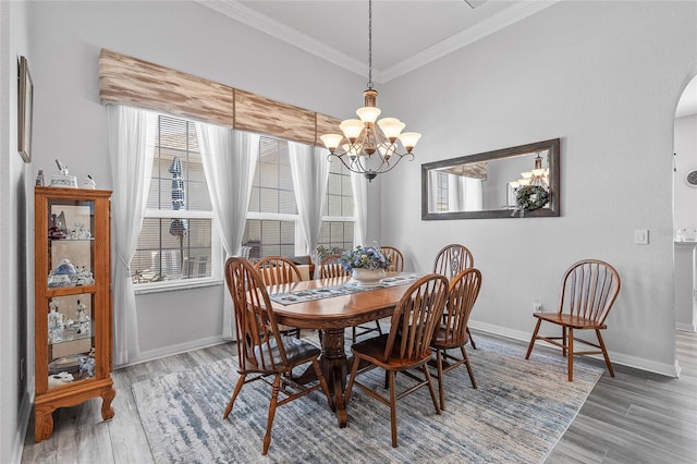 dining area with wood-type flooring, an inviting chandelier, crown molding, and a wealth of natural light