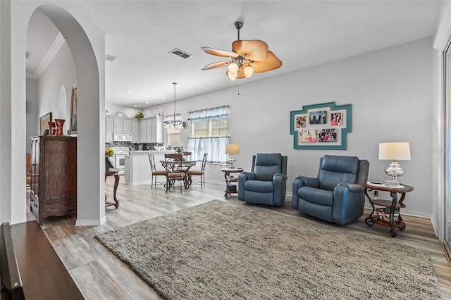 living room with a textured ceiling, ceiling fan with notable chandelier, and light hardwood / wood-style floors