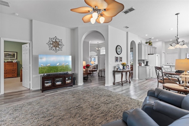 living room with ceiling fan with notable chandelier and light wood-type flooring