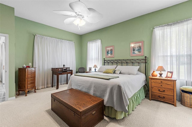 bedroom with ceiling fan, light colored carpet, and multiple windows