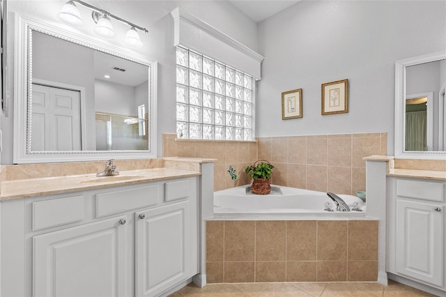 bathroom featuring tile patterned flooring, a relaxing tiled tub, and vanity