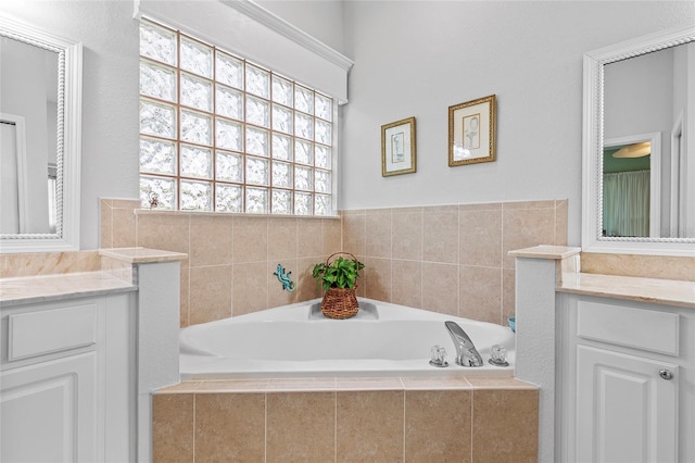 bathroom featuring tiled tub and vanity