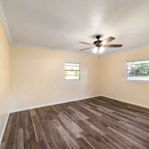 unfurnished room with ceiling fan, dark hardwood / wood-style floors, and ornamental molding