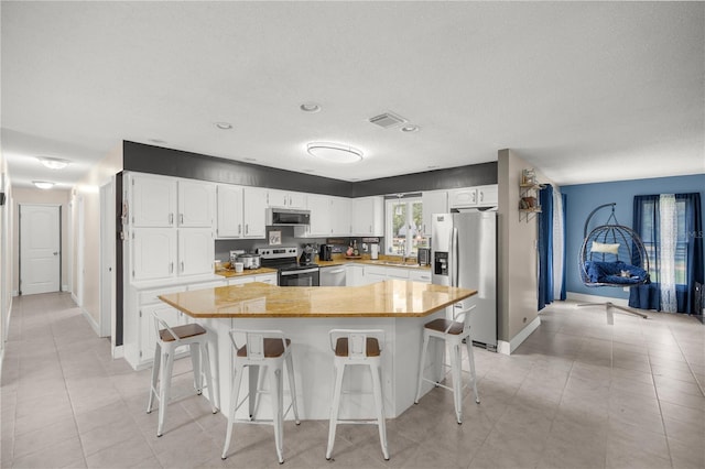 kitchen featuring sink, a textured ceiling, white cabinetry, stainless steel appliances, and a breakfast bar