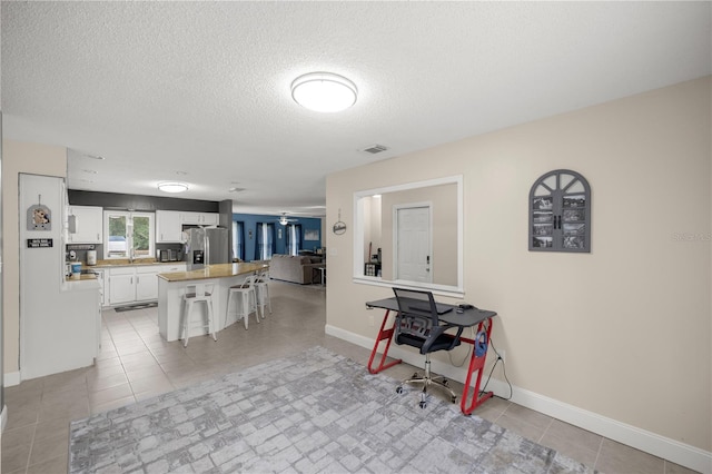 tiled dining area with a textured ceiling and ceiling fan