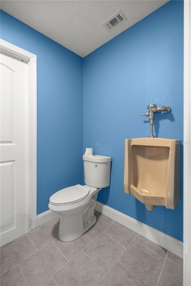 bathroom with a textured ceiling, tile patterned flooring, and toilet