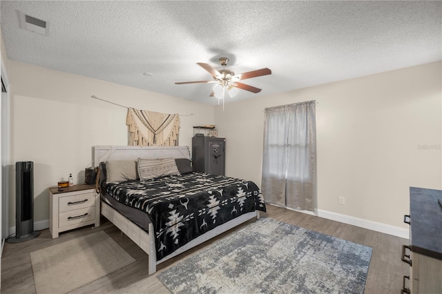 bedroom featuring light hardwood / wood-style flooring, ceiling fan, and a textured ceiling