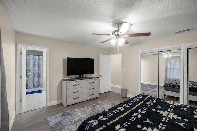 bedroom featuring ceiling fan, a textured ceiling, dark hardwood / wood-style floors, and ensuite bath