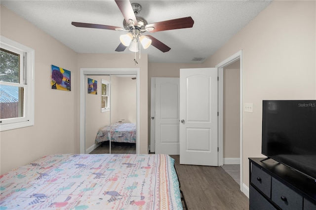 bedroom featuring a textured ceiling, dark hardwood / wood-style flooring, ceiling fan, and a closet