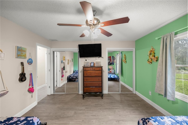 bedroom featuring multiple closets, ceiling fan, hardwood / wood-style flooring, and a textured ceiling