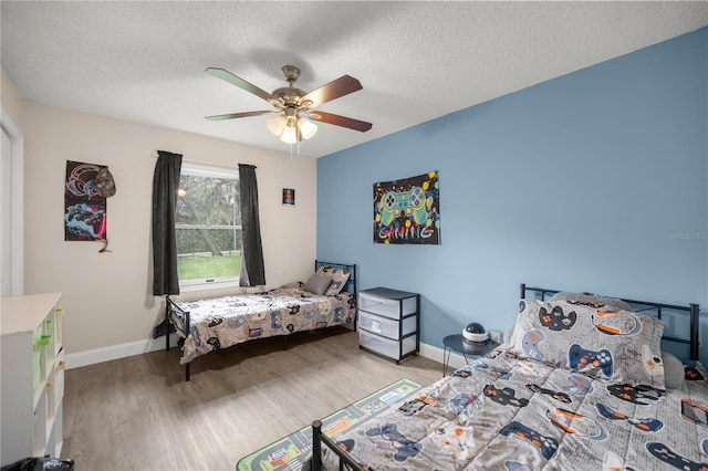 bedroom with ceiling fan, a textured ceiling, and light wood-type flooring