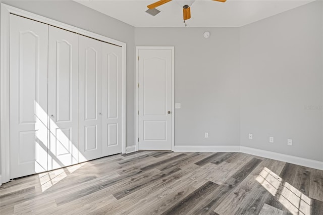 unfurnished bedroom featuring a closet, light hardwood / wood-style floors, and ceiling fan