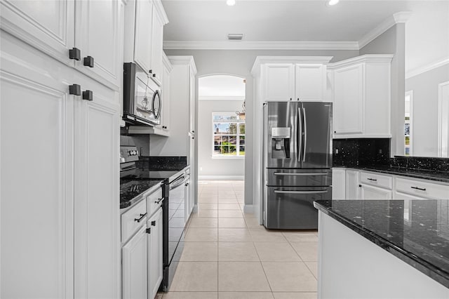 kitchen with stainless steel appliances, dark stone countertops, ornamental molding, white cabinets, and tasteful backsplash