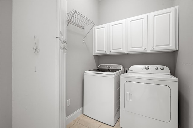 laundry area featuring washer and dryer, light tile patterned floors, and cabinets