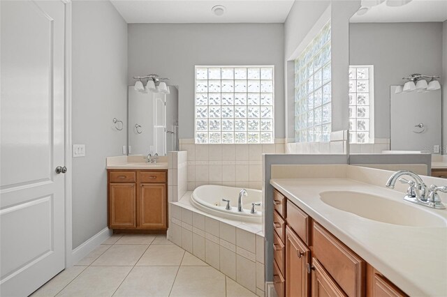 bathroom with vanity, a healthy amount of sunlight, tile patterned flooring, and tiled tub