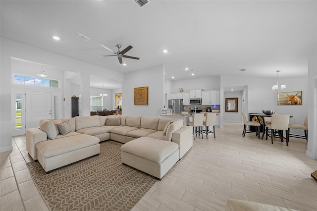 living room with ceiling fan with notable chandelier and light hardwood / wood-style flooring