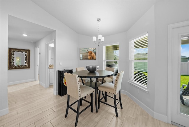 dining area with lofted ceiling, light wood-type flooring, and a notable chandelier