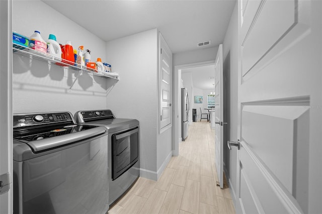 laundry area featuring washer and dryer and light hardwood / wood-style flooring