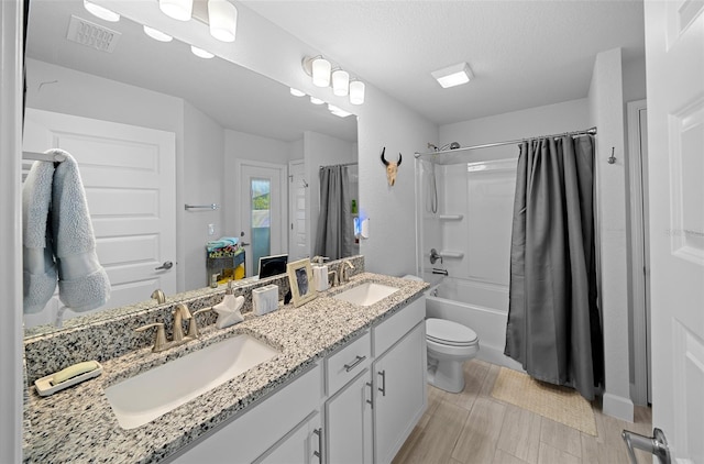 full bathroom with a textured ceiling, vanity, shower / bath combo, and toilet