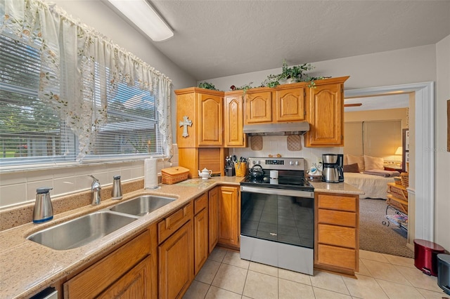 kitchen with light tile patterned flooring, sink, stainless steel range with electric stovetop, a textured ceiling, and backsplash