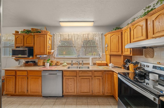 kitchen with a textured ceiling, appliances with stainless steel finishes, light tile patterned floors, and sink