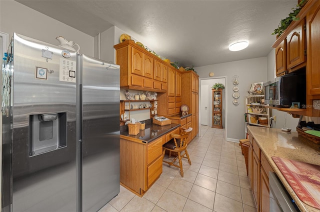 kitchen with a textured ceiling, light tile patterned floors, and stainless steel appliances