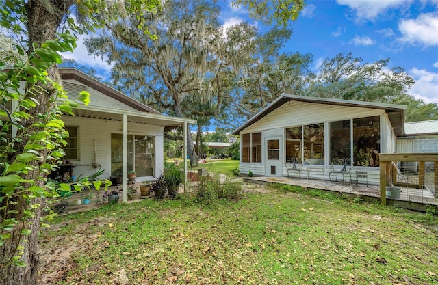 rear view of property featuring a sunroom, a lawn, and a patio area