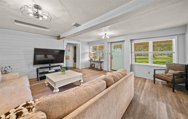 living room featuring light wood-type flooring, a textured ceiling, and an inviting chandelier