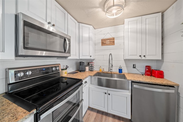 kitchen with a textured ceiling, sink, stainless steel appliances, and white cabinets