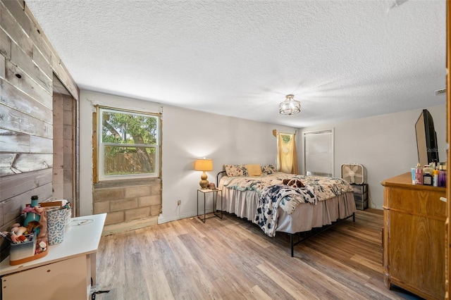 bedroom with a textured ceiling and light hardwood / wood-style floors