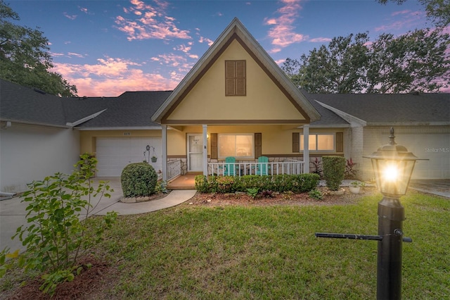 view of front of house with a yard, a porch, and a garage