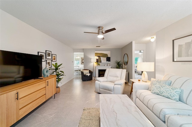 living room with ceiling fan, plenty of natural light, and a textured ceiling