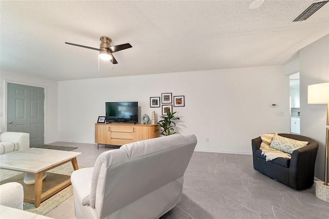 living room with ceiling fan and a textured ceiling