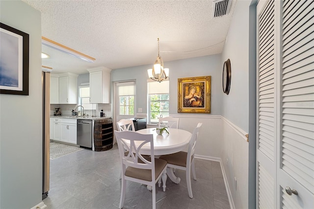 dining space featuring a notable chandelier, a textured ceiling, and sink